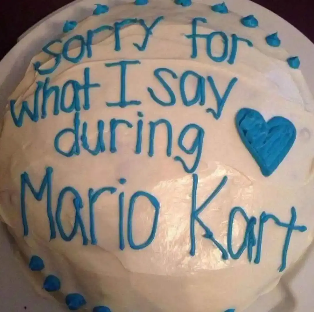 a white cake decorated with blue icing saying "sorry for what I say during Mario Kart"