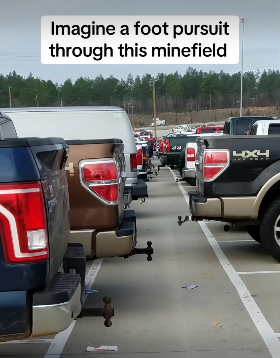 A picture of pickup trucks with tow hitches all backed in across a parking lot with the text “Imagine a foot pursuit through this minefield”
