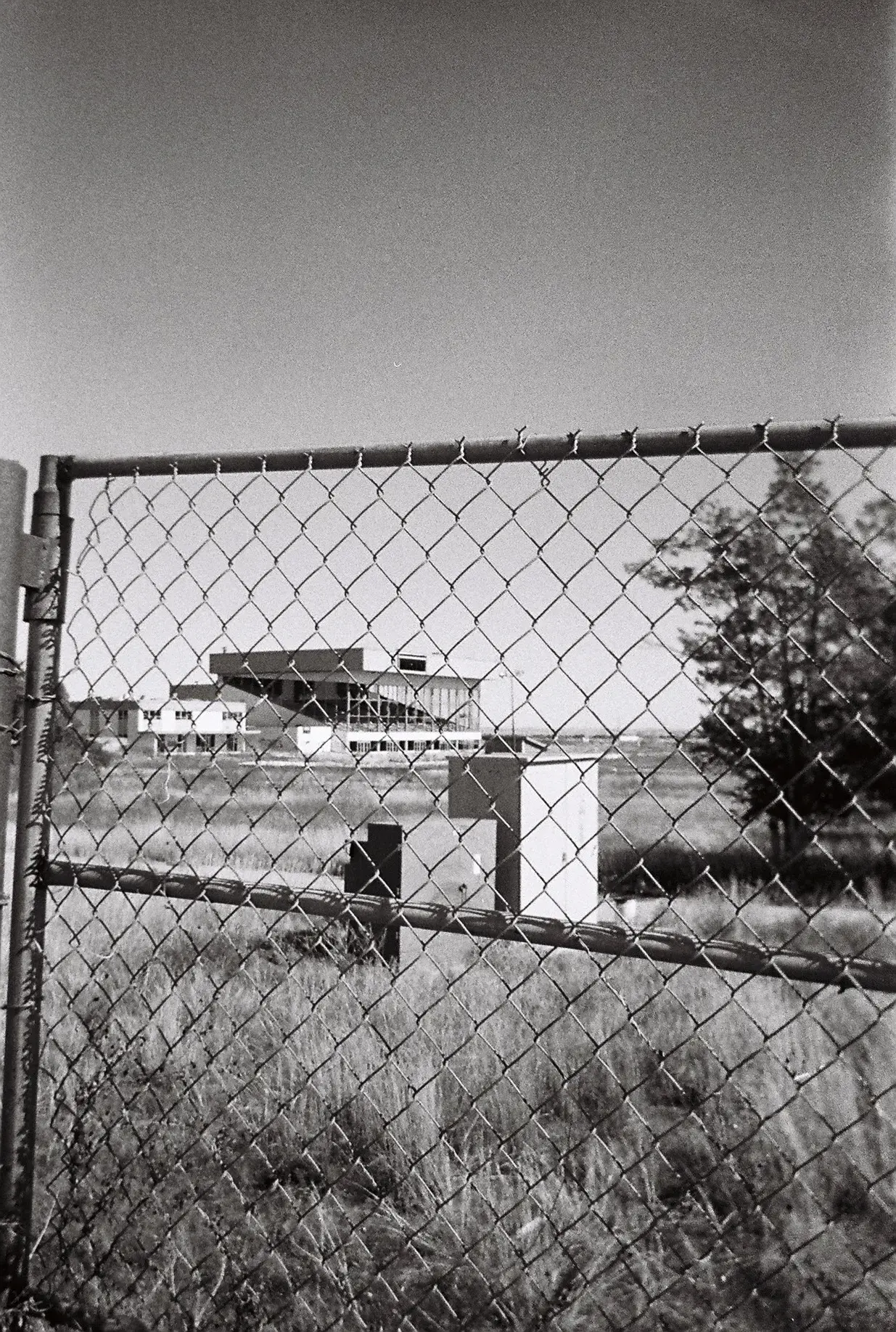 An abandoned dog track as seen through a chain-link fence.