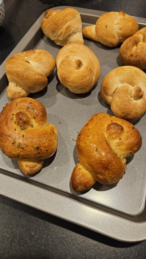 Baked and buttered garlic knots on a baking tray